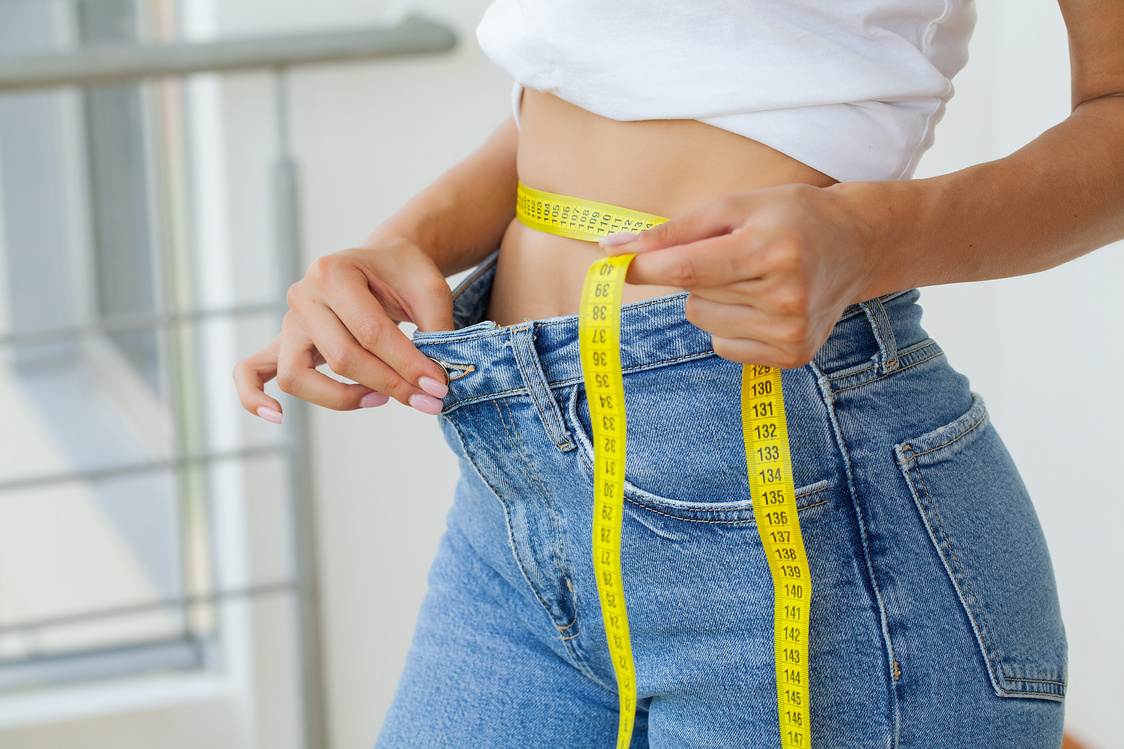 Fit Person in Loose Jeans Measuring Waist